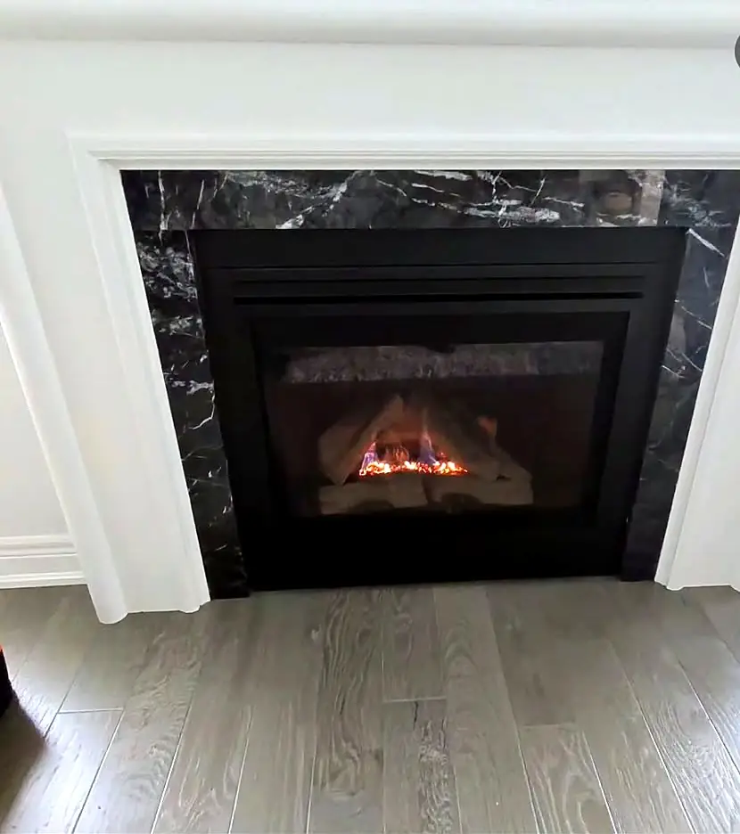 Rebuilt gas fireplace in a white mantel with a black marble surround