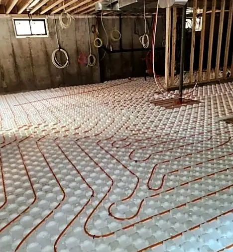 Radiant heating loops laid across insulation boards in a basement